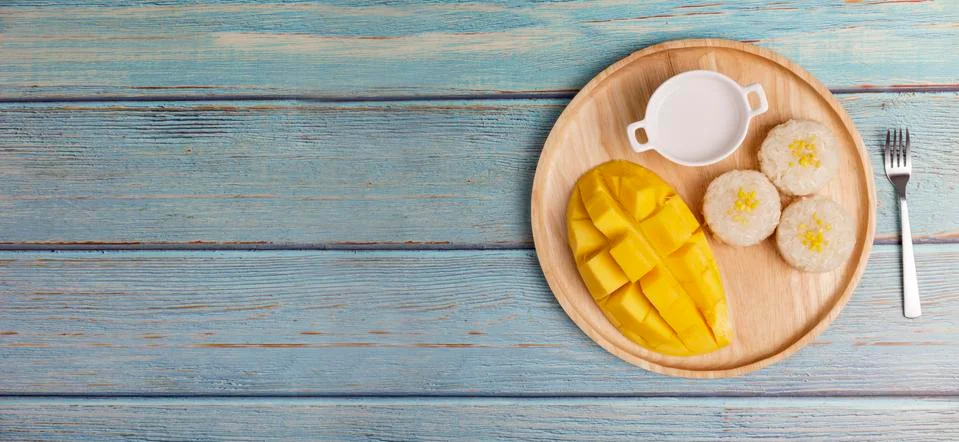 Top view Yellow half  mango with small fork. Mango fruit cubes on the Blue wo Stock Photos