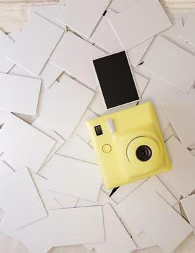 Top view of a yellow instant camera and film photo on the pile of white pap.. Stock Illustration