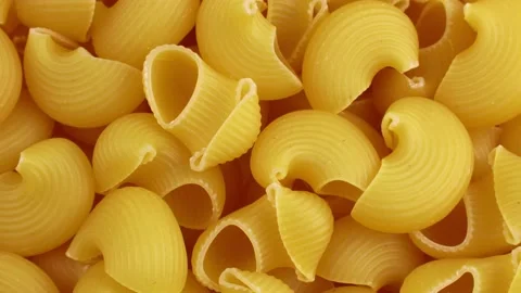 Top view of yellow uncooked pipe rigate snail shape Italian pasta rotation Stock Footage 233998361