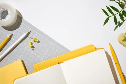 Top view of a yellow workspace with an open notebook, pen, and pencils on a.. Stock Photos