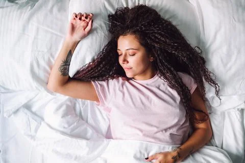 Top view of young afro haired woman sleeping in morning lying on bed with snow Stock Photos