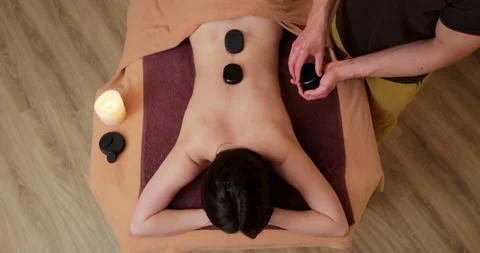 Top view of young and beautiful woman gets hot stone massage therapy in the spa Stock Footage 166686629