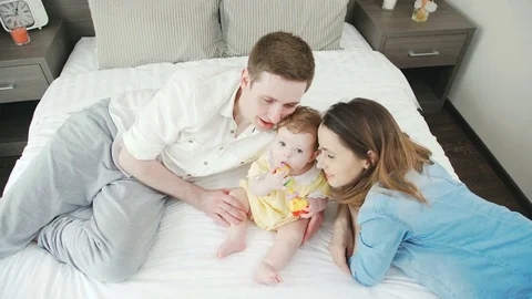 Top view: young and happy family with a baby in bed together Video stock 75949982