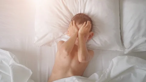 Top view of a young boy yawning and stretching in bed Stock Footage 116395480
