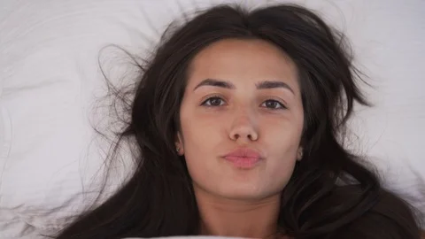 A top view of a young brunette's face. The white blanket is taken away. Stock Footage 93790761