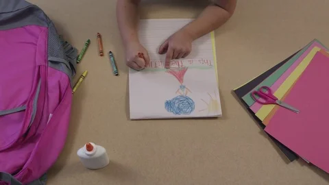 Top view of young child drawing pictures and construction paper and glue Stock Footage 80132097