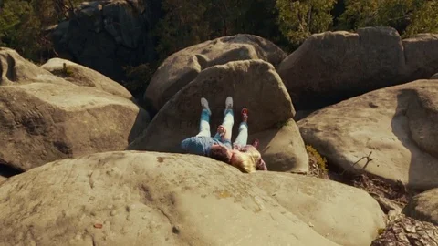 Top view of a young couple lying on the mountain stone by the dangerous abysm Video stock 71779398