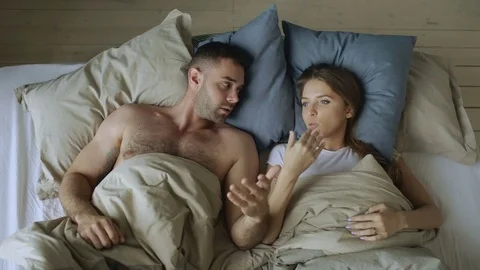 Top view of young couple lying in bed upset and argue each other Stock Footage