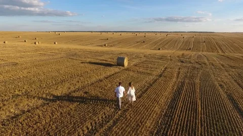 Top view of a young couple walking in a field at sunset Stockbeeldmateriaal 99819882