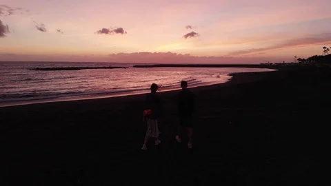 Top view of a young couple walking along a beautiful volcanic sand beach at Vídeo Stock 108755027