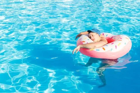 Top view of young drunk guy swim with pink circle in pool. drunk guy on vacat Stock Photos