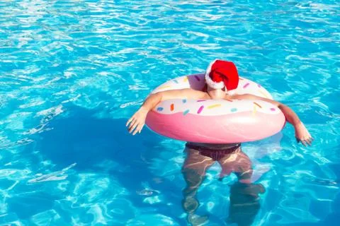 Top view of young drunk guy in christmas hat swim with pink circle in pool. d Stock Photos