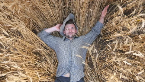 Top view of young farmer lying on wheat stems and resting at cereal field. Happy Vídeo Stock 135225607
