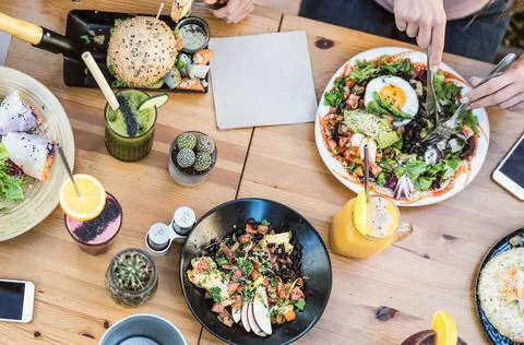 Top view of young friends eating healthy lunch in bar restaurant Stock Photos