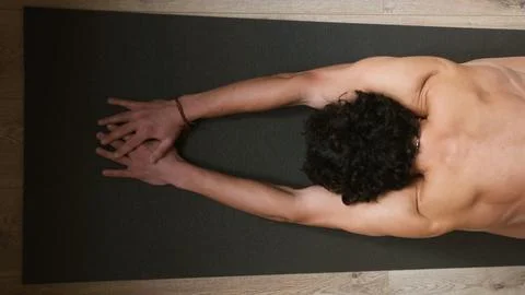 Top view of a young man with a bare torso at a warm-up before a yoga workout. Stock Photos