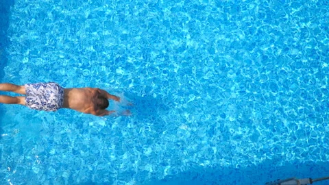 Top view of young man jumping in pool and splashing crystal clear water Stock Footage 109165538
