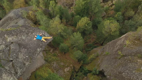 Top view A young man lies on the edge of a cliff with his eyes closed. Stock Footage 149084103