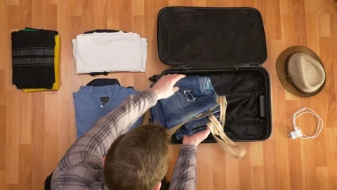 Top view of young man preparing clothes for trip and packing it into a suitca Stock Footage 74087275