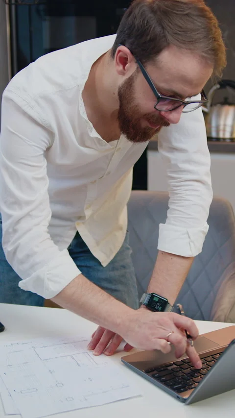 Top view young man working on project on laptop, standing at shared table in mod Stock Footage 334679776