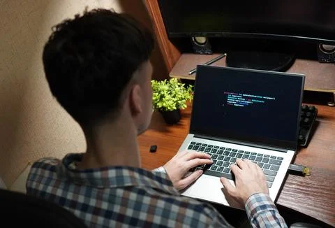 Top view of a young programmer working with his hands on a laptop with a gr.. Foto stock