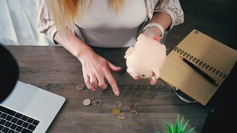 Top view of a young woman learning personal finance by counting coins from .. Stock Footage 333591989