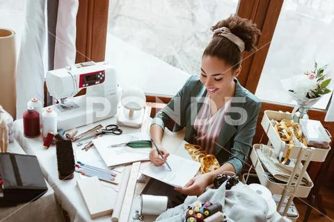 Top view of young woman tailor with not pad is drawing by pencil Stock Photos