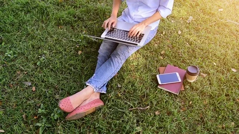 Top view of young woman using computer laptop while sitting on grass. Stock Footage 83699295