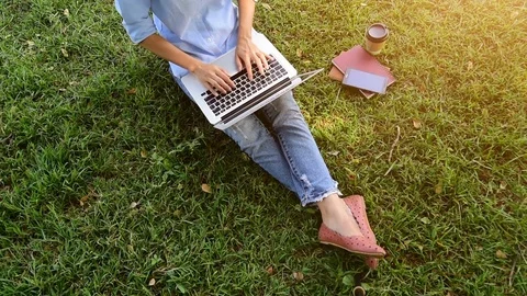 Top view of young woman using computer laptop while sitting on grass. Stock Footage 83699300