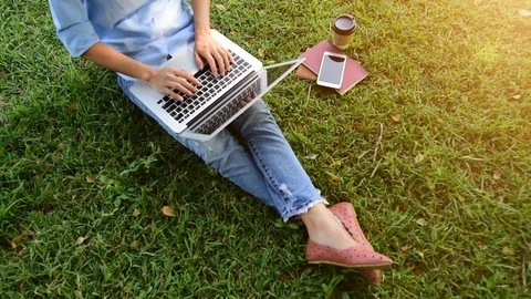 Top view of young woman using computer laptop while sitting on grass. Vidéo 83699481