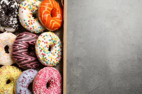 Top view of yummy donuts with sprinkles in box, space for text Stock Photos