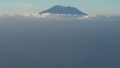 Top of volcano coming out of clouds with island coast below Stock Footage 112482574