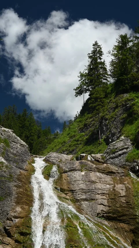 The top of a waterfall and a cloud moving over the blue sky in summer, vertical Stock-Footage 260875159