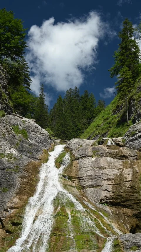 The top of a waterfall and a cloud moving over the blue sky in summer, vertical Video stock 260875167