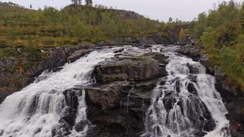 Topdown view of lone man by roaring waterfall in colorful Norway fall Video stock 321029351