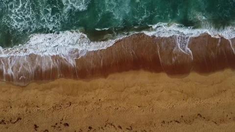 Topdown view of ocean waves crashing on a sandy beach with foamy white water Stock Footage 318323851