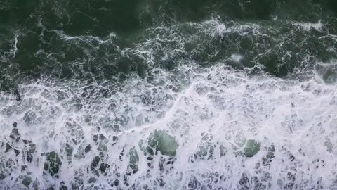 Topdown view of turbulent ocean waves and swirling seafoam patterns on deep Stock Footage 305558803