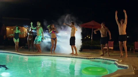 Topless Caucasian males and females in swimsuits dancing jumping at pool at Stock Footage