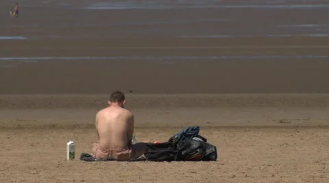 Topless man sitting alone on beach Stock Footage 51749635
