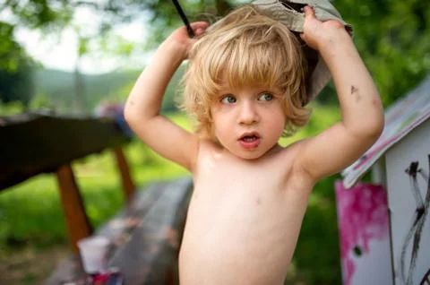 Topless small blond boy with hat painting outdoors in summer. Stock Photos