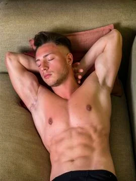 Topless young man on sofa Stock Photos