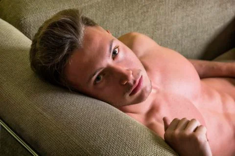 Topless young man on sofa Stock Photos