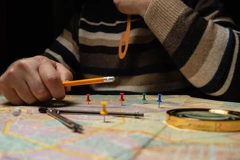 A topographer is focused on a map, placing colored pins on marked locations.. Stock Photos