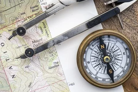 Topographical map on a wooden surface with compasses, measuring tool on top Foto stock