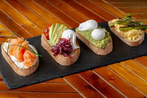 Topped Bread with different toppings salmon cream cheese, eggs avocado eggs Stock Photos