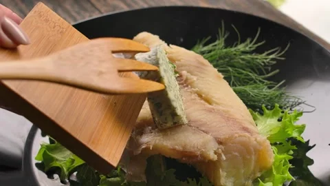Topping a hot cod fillet with a slice of garlic dill butter Stock Footage 328309850