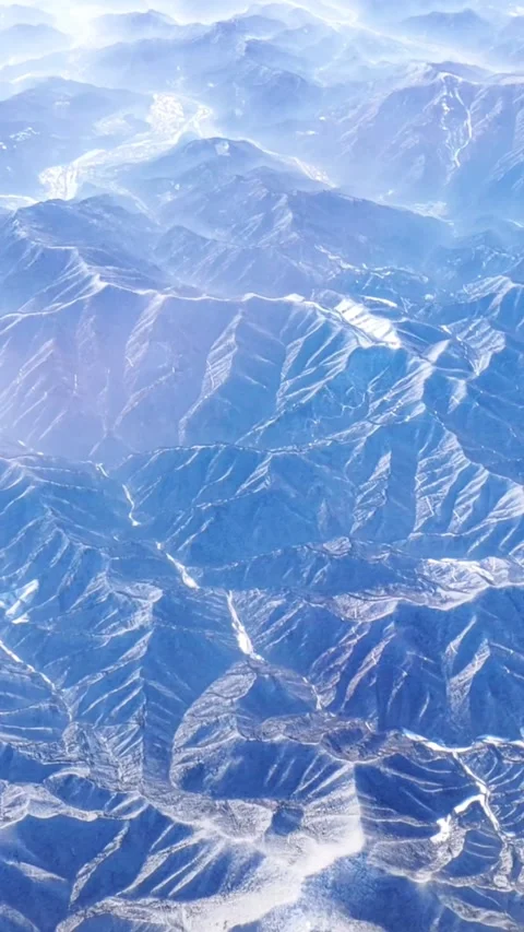 The tops of the mountains covered with snow view from the window of the plane. Stock-Footage 345897053