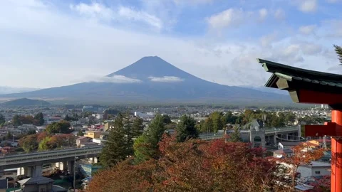 Torii frames Mount Fuji above Fujiyoshida with cars and bright autumn trees Stock Footage 323822802