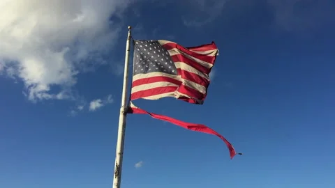 Torn American Flag in wind bright blue sky Stock Footage 140842042