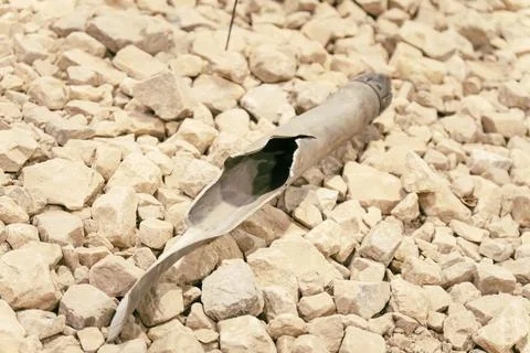 Torn artillery shell on the stone ground. Stock Photos