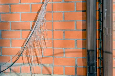 Torn black wire of electrical communications under the weight of icicles. Stock Photos